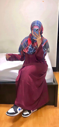 Woman in maroon abaya and plaid hijab taking mirror selfie, casual modest outfit