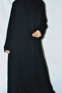 Woman wearing a plain black open abaya with long sleeves, modest everyday style