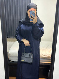 Woman in navy blue open abaya with black hijab holding black handbag in mirror selfie