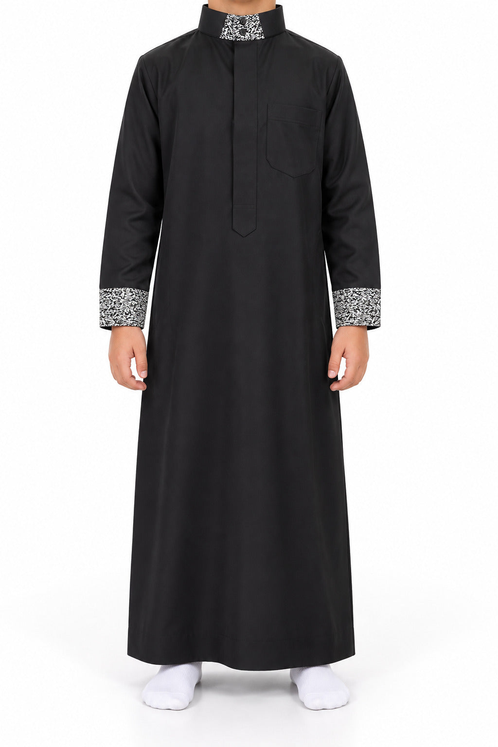 Boy wearing a black Saudi thobe with black and white patterned collar and cuffs, front view