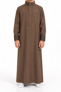 Boy wearing a brown Saudi thobe with geometric patterned collar and cuffs, front view