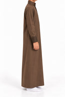 Side view of a boy wearing a brown Saudi thobe with geometric patterned collar and cuffs