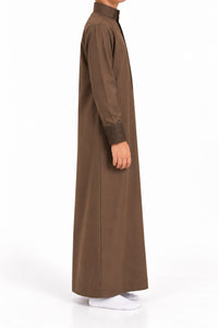 Side view of a boy wearing a brown Saudi thobe with geometric patterned collar and cuffs