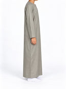 Side view of a boy wearing a cement grey Omani thobe