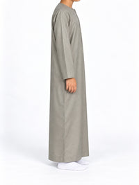 Side view of a boy wearing a cement grey Omani thobe