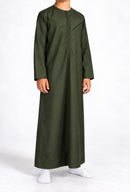 Boy wearing a forest green Omani thobe with curved chest stitching, front view