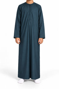 Boy wearing a dark marine blue Omani thobe with curved chest stitching, front view