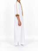 Side view of a boy wearing a white Moroccan thobe with gold sleeve trim and sleeves extending below the elbows