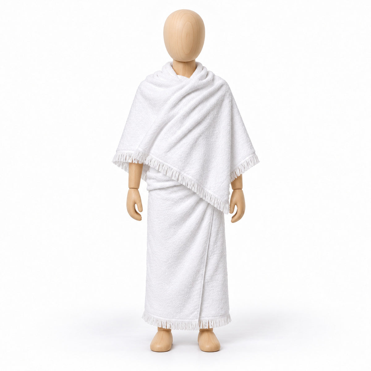 White two-piece children’s ihram with fringed edges displayed on a wooden child-sized mannequin